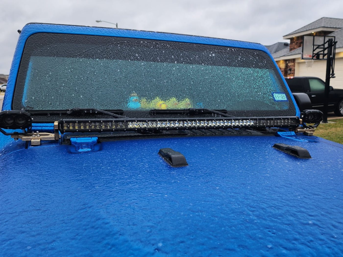 LED light bar and two pod lights mounted at the base of a blue Jeep's windshield